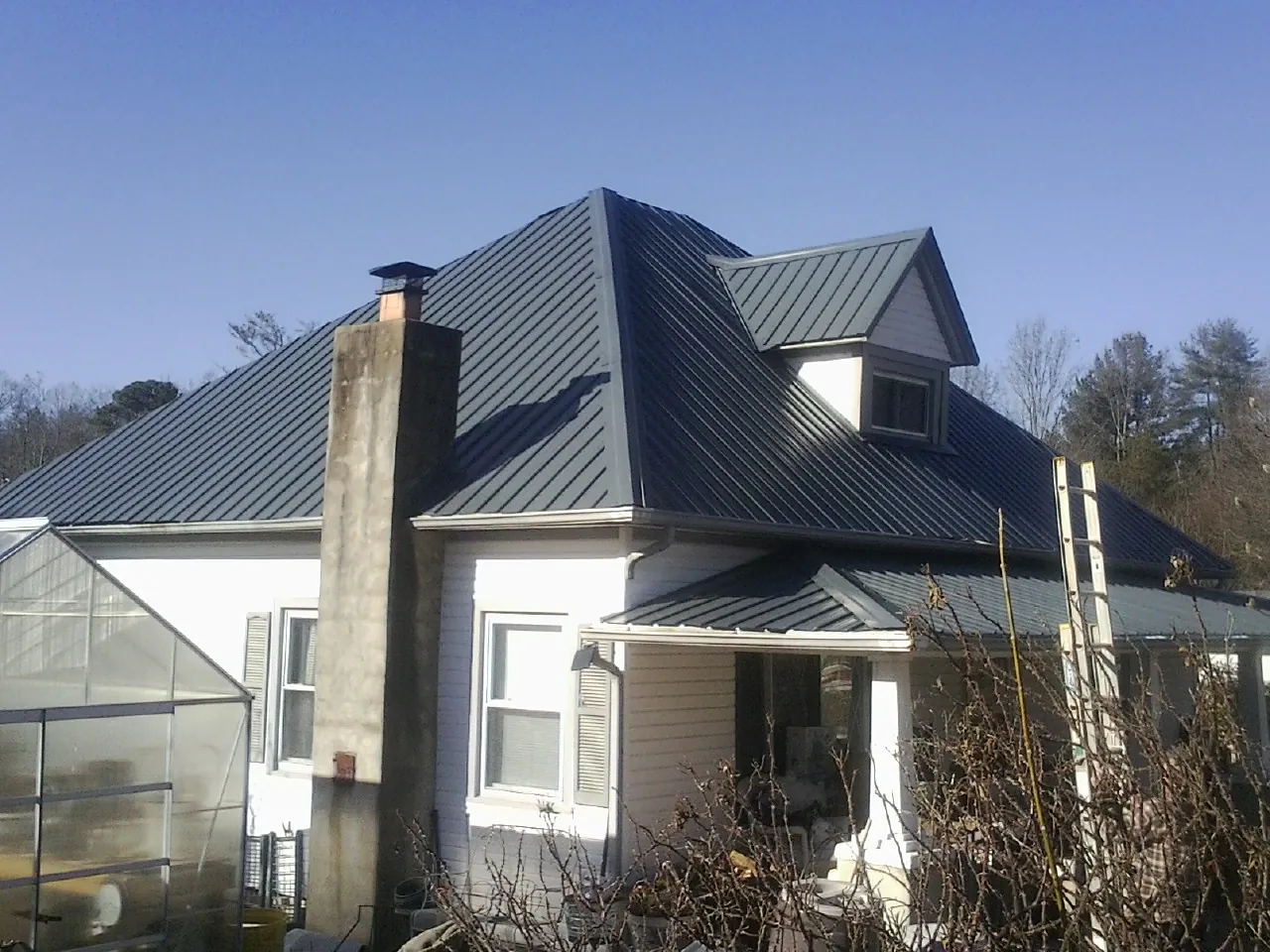 Dark blue standing seam metal roof on a white farmhouse with dormer — Slate & Tile Roof Repair by Roofing Brothers in Signal Mountain