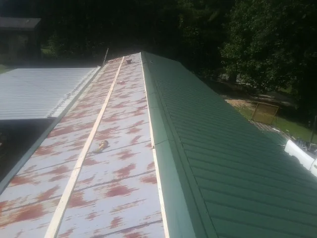 Old rusted panels beside newly installed green metal roofing — Wind Damage Roof Repair by Roofing Brothers in Signal Mountain