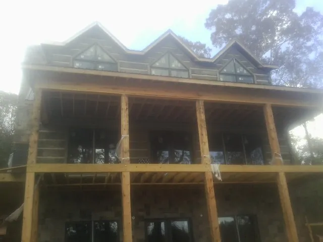 Dormers and porch framing on a large log home under construction — Roof Coating work by our crew in Signal Mountain
