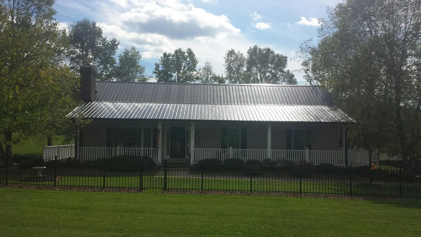Gray metal roof on a brick ranch with a full width front porch — Gutter Guard Installation work by our crew in Signal Mountain