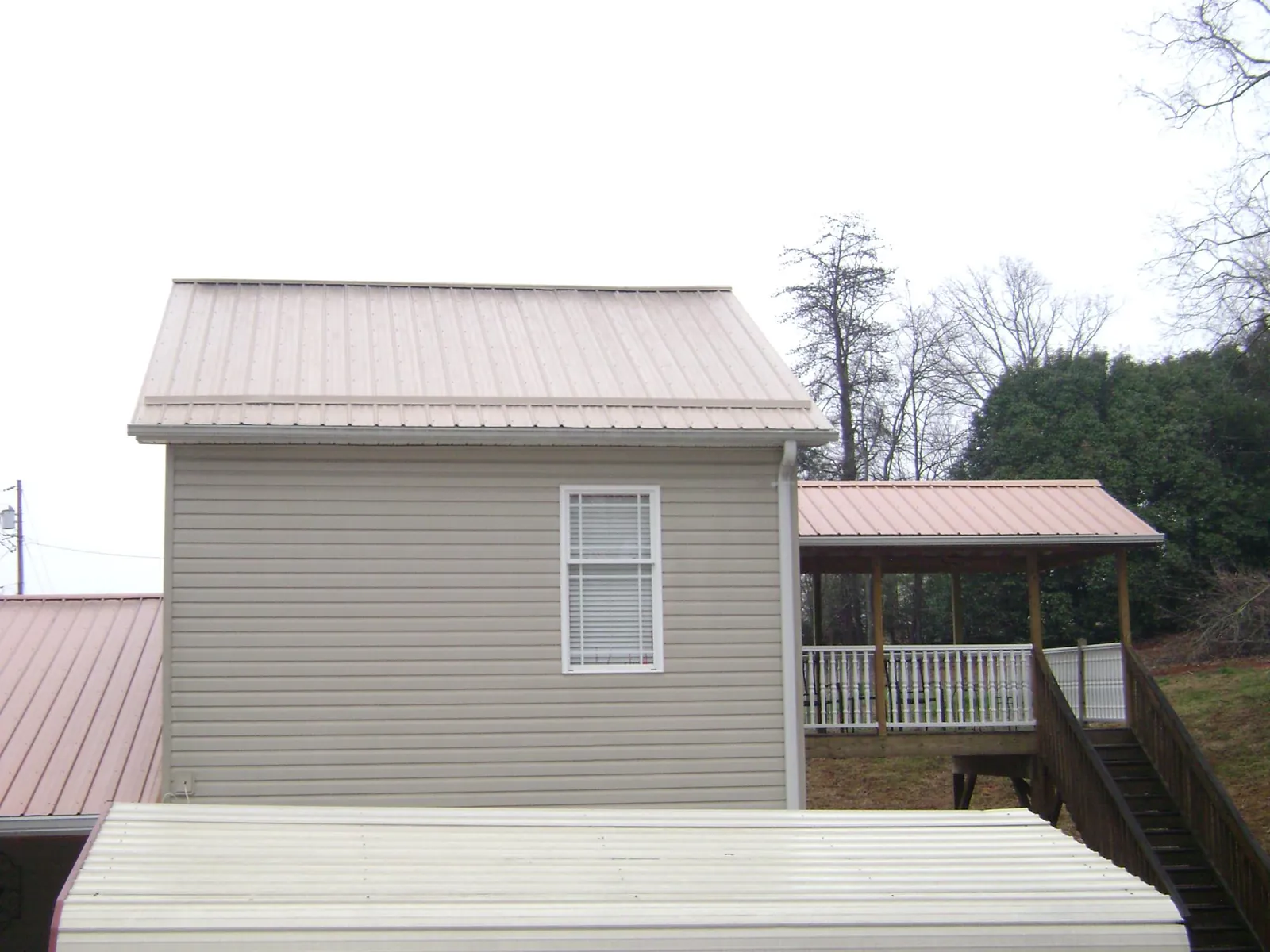 Tan metal roofs on a two story addition and attached porch, from a Roof Replacement job in Signal Mountain