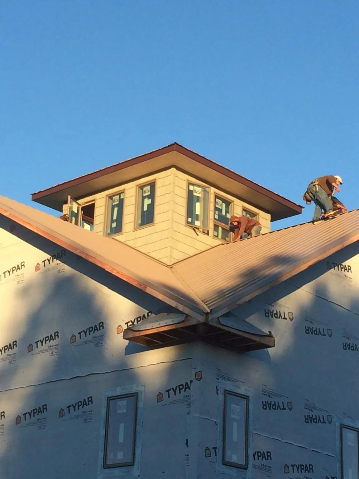 Roofers working around a rooftop cupola on a new metal roof at sunset — Roof Waterproofing in Signal Mountain by Roofing Brothers